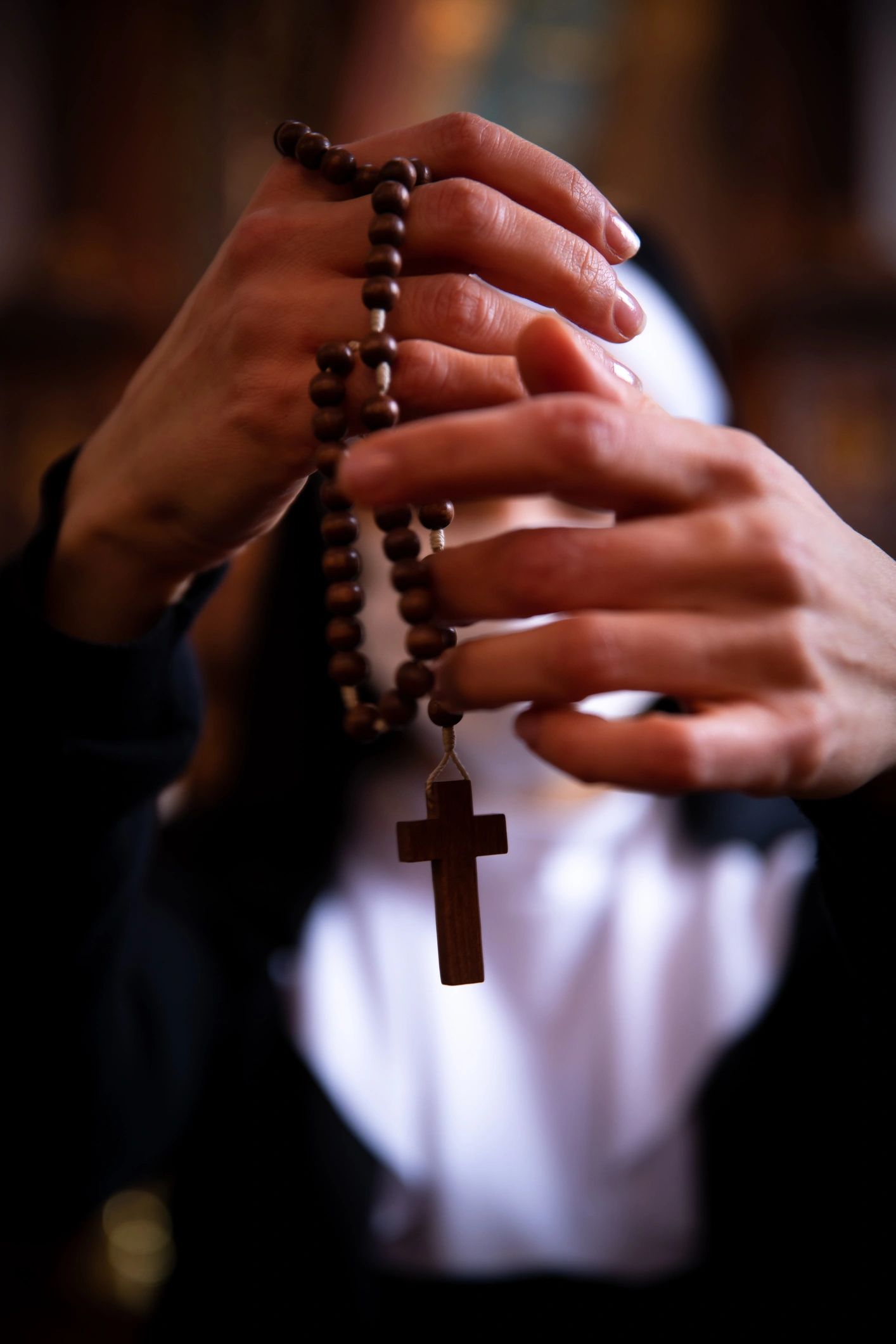 Hands holding rosary beads in prayer